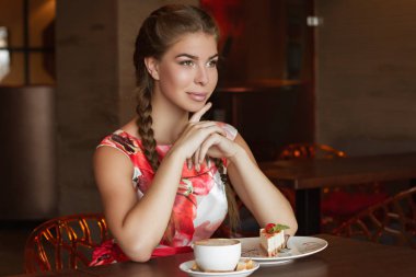 Bir kupa kahve ve peynirli kekle güzel bir kız.