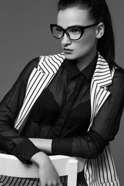 Zarif gözlük ve takım elbise güzel çekici kadın oturuyor. siyah beyaz fotoğraf