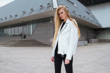 Sarışın kadın kentsel arka planda. Güzel genç kız sokakta bekleyen bir beyaz deri ceket giyiyor.