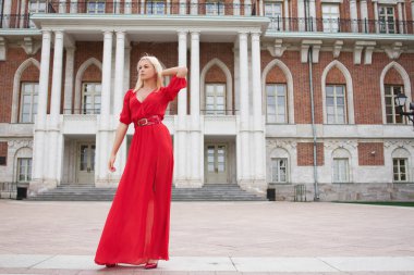 Uzun kırmızı elbiseli güzel ve zarif kız Ortaçağ Kalesi ortasında duruyor