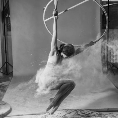 Havada jimnastik yapan taytlı, genç, ince bir kız ve beyaz tozun ellerini bulut şeklinde fırlatıyor..