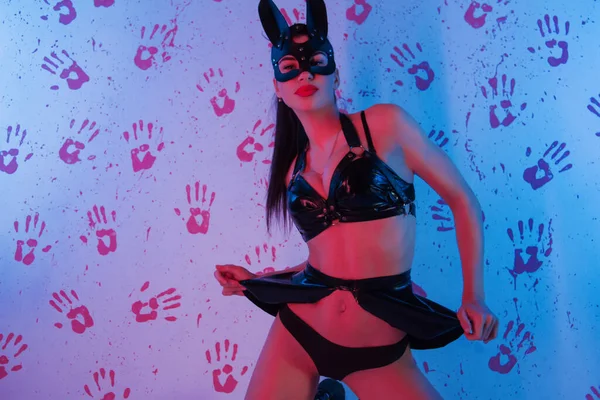 Çekici esmer kadın seksi kıyafetler içinde poz veriyor.