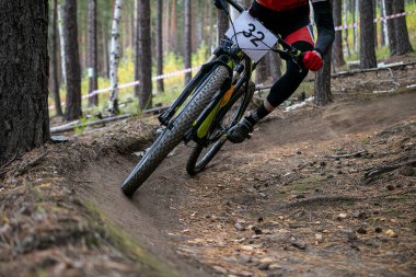 Bisikletçi dağ bisikleti yarışında keskin virajlı orman yolunda gidiyor.