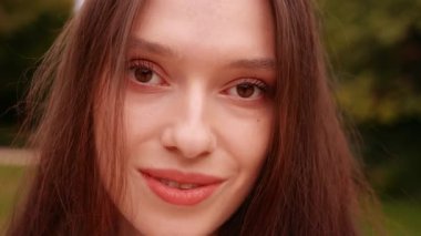 Kendine güvenen genç bir kadın kameraya bakıp portreyi kapatıyor, sonra gülümsüyor, kendinden emin bir kadın modeli, güzellik, yaşam tarzı, zarafet, doğal ifade, pozitiflik..