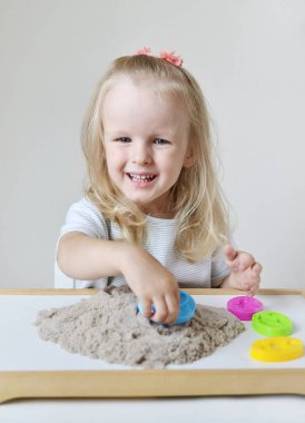 Eve erken eğitim okul geliştirme çocuk oyunu için hazırlanıyor kinetik kumla oynayan küçük beyaz kız