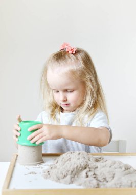 Eve erken eğitim okul geliştirme çocuk oyunu için hazırlanıyor kinetik kumla oynayan küçük beyaz kız