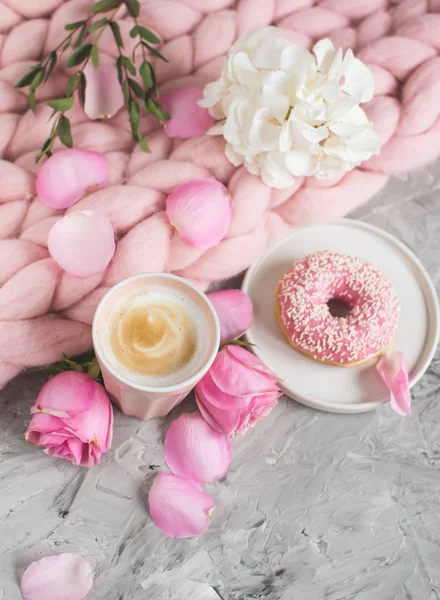 Cup with cappuccino, doughnut, pink pastel giant blanket, flowers, bedroom, morning concept