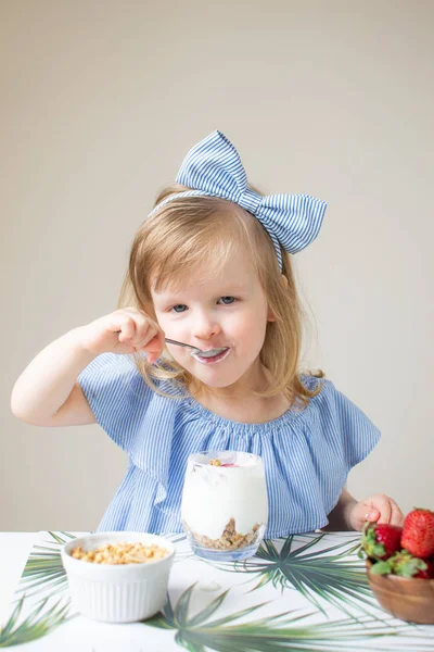 少し白人のブロンドの女の子の健康的な食事朝食自宅ミルク果実ストロベリー ブルーベリー ギリシャ ヨーグルトのミューズリー ダイエット ビタミン夏食品コンセプト — ストック写真