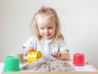 Eve erken eğitim okul geliştirme çocuk oyunu için hazırlanıyor kinetik kumla oynayan küçük beyaz kız