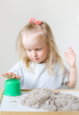 Eve erken eğitim okul geliştirme çocuk oyunu için hazırlanıyor kinetik kumla oynayan küçük beyaz kız