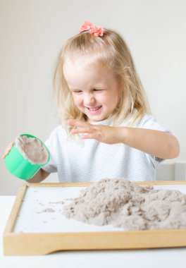 Eve erken eğitim okul geliştirme çocuk oyunu için hazırlanıyor kinetik kumla oynayan küçük beyaz kız