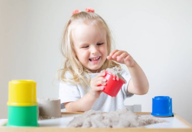 Eve erken eğitim okul geliştirme çocuk oyunu için hazırlanıyor kinetik kumla oynayan küçük beyaz kız