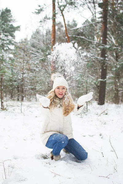 Kış giysileri içinde genç mutlu kadın Karlı Ormanda yürür