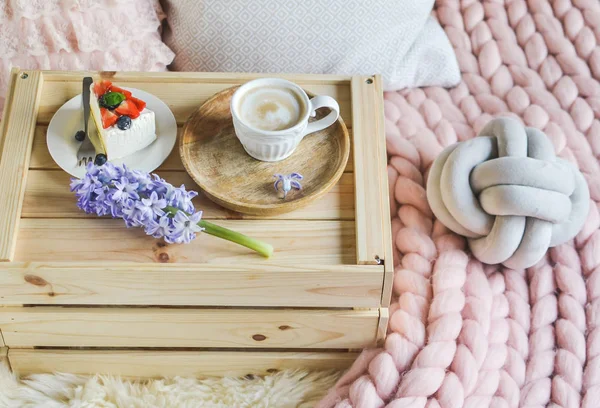 ケーキとカプチーノ パステル ピンクのメリノ ウールの毛布コーヒー ヒヤシンスの花朝概念とベッドでの朝食 — ストック写真