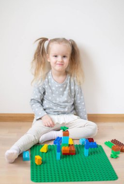 Eve erken eğitim okul gelişimi için hazırlanıyor plastik renkli tuğlalar ile oynayan beyaz kız