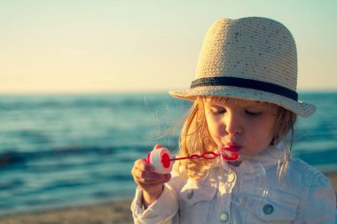 Küçük kız denizde sabun köpüğü üfleme. Tonda fotoğraf