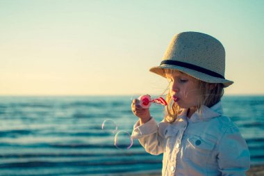 Küçük kız denizde sabun köpüğü üfleme. Tonda fotoğraf