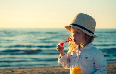 Küçük kız denizde sabun köpüğü üfleme. Tonda fotoğraf