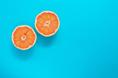 Mavi arka plan üzerinde iki kırmızı portakal greyfurt dilimleri, düz yatıyordu, minimalizm, yaz yaratıcı kavramı
