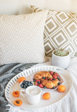 Yatakta sabah kahvaltısı, bir fincan kahve, kruvasan, taze çilek, sulu tencere. Sağlıklı gıda kavramı. İskandinav tarzı