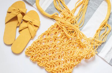 El yapımı sarı makrame, plaj havlusu, beyaz arka plan üzerinde sandalet, Çevre dostu. Modern yaz seyahat konsepti