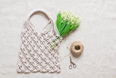 Keten arka plan üzerinde el yapımı macrame çanta, Çevre dostu. Nakış. Modern yaz konsepti. Lily vadi buketi 