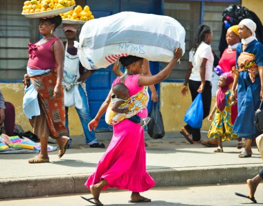 Accra, Gana / 1,2018 olabilir: bir çocuk için onu geri bağlı, bir kadın büyük bir çanta başına taşır.