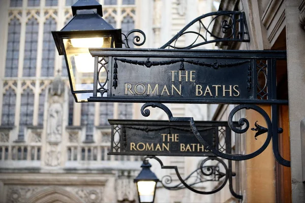 View of Vintage Signs and Street Lamps at the Entrance of the Historic Roman Baths in the City of Bath in Somerset England