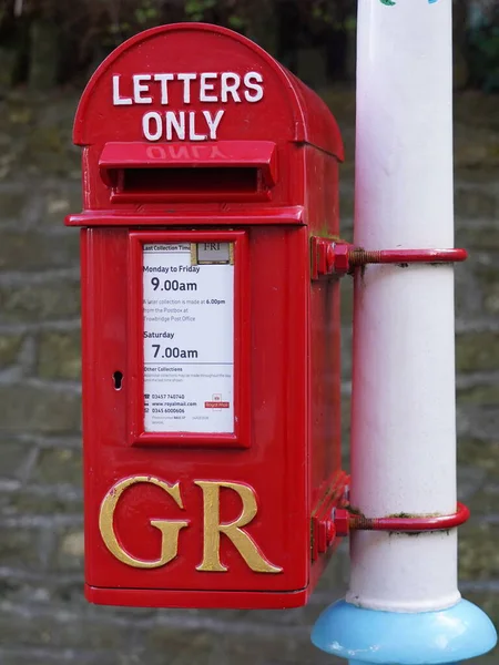 Frome, UK - January 5, 2017: A traditional Royal Mail red pillar box is seen outside a Post Office. Founded in 1516 Royal Mail iconic post boxes are ubiquitous throughout Britain and the Commonwealth.