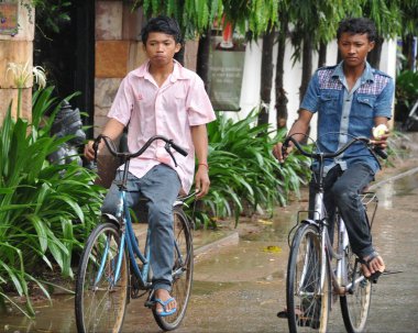 Siem Reap, Kamboçya - 13 Ağustos 2013: Erkekler şehir merkezinde bisiklet sürüyor.