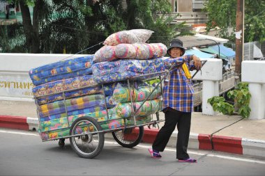 BANGKOK - 27 Mayıs 2013: Çarşaf satan bir tüccar, şehir merkezi sokak hükümet istatistiklerine göre Tayland 'ın başkentinde kayıtlı 16.000 sokak satıcısı ile birlikte bir el arabası itiyor.