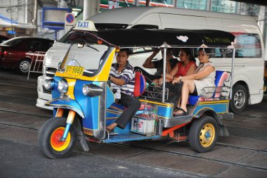 Bangkok, Tayland - 22 Mayıs 2013: Üç tekerlekli bir tuk tuk taksisi Tayland başkentindeki bir caddede yolcu taşıyor. Tuk tuk 'lar genellikle insanları ve malları başkentte taşımak için kullanılır..