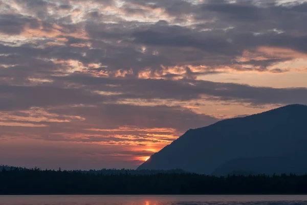 Matahari merah terbenam di atas gunung saat matahari terbenam di danau Frolikha — Stok Foto