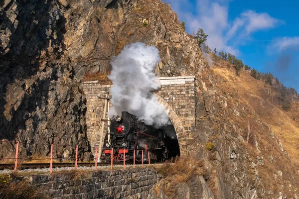 Uma velha locomotiva a vapor sai do túnel — Fotografia de Stock