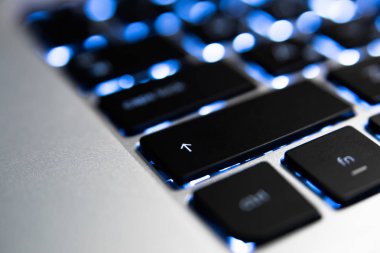 Kara ışıklı laptop klavye ve gümüş gövde, yakın çekim, makro