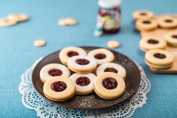 Cookies with jam, biscuits on a brown plate on a blue tablecloth