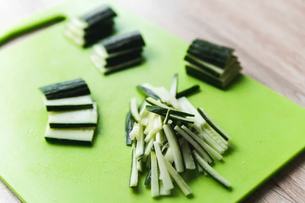 Sliced cucumber on green board on a wooden table, closeup