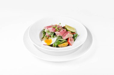 Ton balığı, marul, domates, yumurta ve beyaz zemin üzerine bir tabak patates salatası