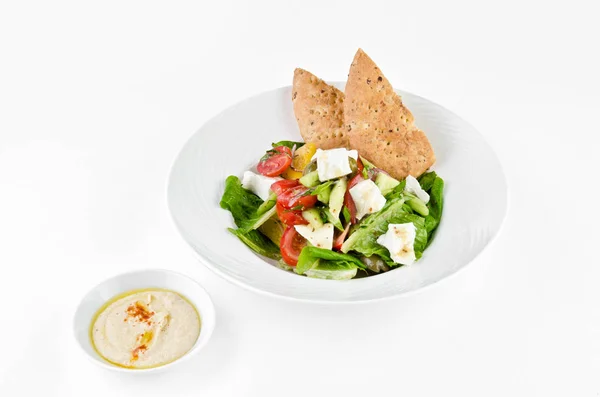 フェタチーズ リグーリア州のオリーブ トルティーヤのエンドウ豆とフムスのギリシャのサラダ 白い背景のプレート — ストック写真