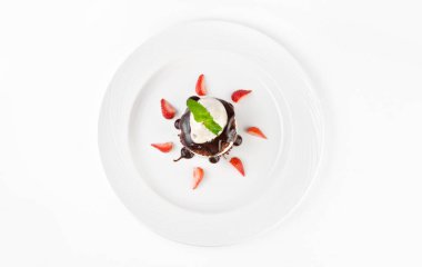 Çikolata sünger kek ile tatlı, vanilya krem, kiraz, dondurma ve çilek beyaz bir arka planda bir plaka üzerinde, üst görünüm