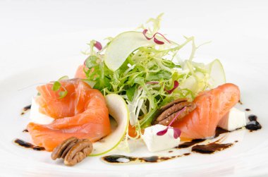 Beyaz bir arka planda bir plaka üzerinde beyaz peynir, yeşil elma, pekan ve soya sosu ile marine somon, yakın yukarı