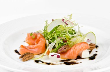 Beyaz bir arka planda bir plaka üzerinde beyaz peynir, yeşil elma, pekan ve soya sosu ile marine somon, yakın yukarı