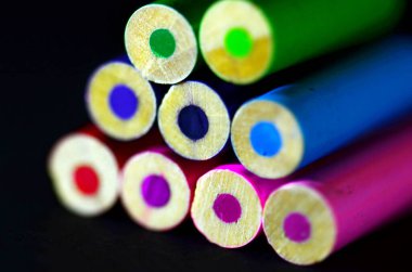 Siyah bir arkaplanda izole edilmiş renkli kalemlerin sanatsal makro görüntüsü.