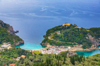 Bulutlu bir gökyüzünün altında sahili ve turkuaz suyu olan Yunanistan 'ın Korfu adasının manzarası..