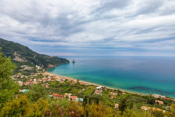 Bulutlu bir gökyüzünün altında sahili ve turkuaz suyu olan Yunanistan 'ın Korfu adasının manzarası..