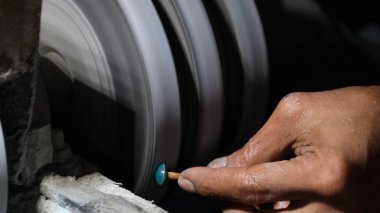 Mücevher tüccarı bir taş parlatıcı makinesinde taş şekillendiriyor..