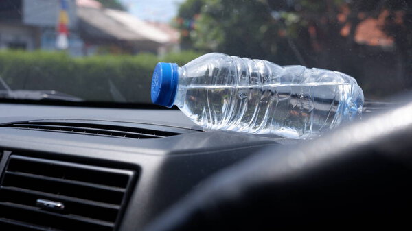 The bottle in the car that is exposed to the sun.