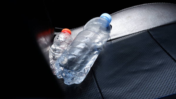 The bottle in the car that is exposed to the sun.