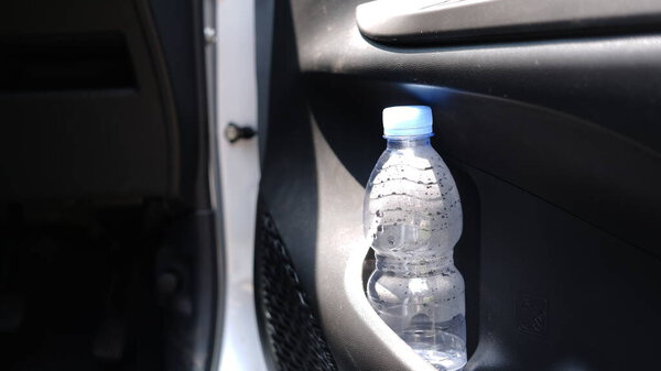 The bottle in the car that is exposed to the sun.