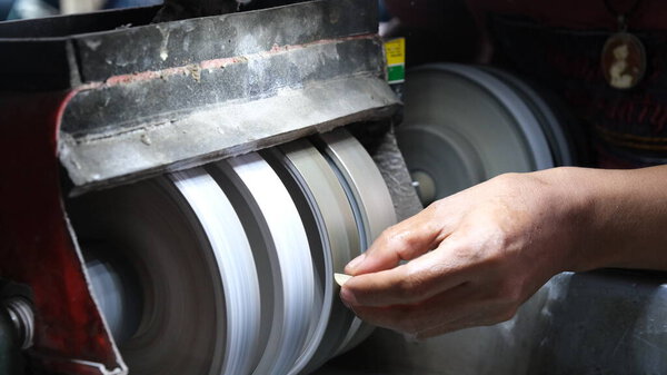 Торговец драгоценными камнями формирует камень на каменной полировальной машине.